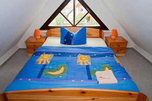 Une chambre à coucher avec un lit, deux tables de chevet et une fenêtre située au-dessus du lit.