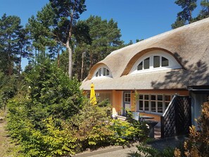 Une maison avec un toit de chaume, un balcon et un jardin.