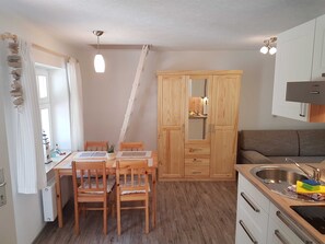 Une cuisine compacte avec des meubles en bois, une table à manger avec des chaises, un four encastré et un évier.