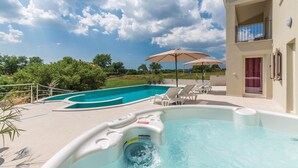 A swimming pool with lounge chairs and a hot tub, surrounded by a building with a balcony. - Cozy home in Visnjan with sauna (Visnjan)