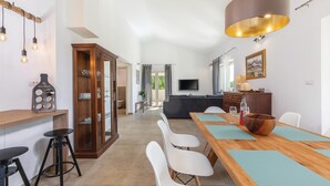 A modern dining area with a wooden table, white chairs, and a large pendant light. - Cozy home in Visnjan with sauna (Visnjan)
