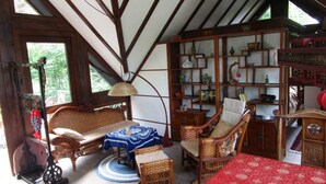 A traditional room with wooden beams, a sofa, a chair, a table, and a bookshelf.