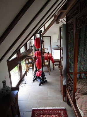 A room with a sloped ceiling, a wooden bed, a red lantern stand, and a patterned wall. - Vacation home in the countryside (with e-car charging station) - Holiday home in the countryside (Morsbach)