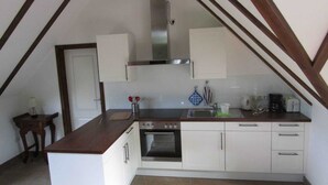 A compact kitchen with white cabinets, a built-in oven, and a small island with a sink.