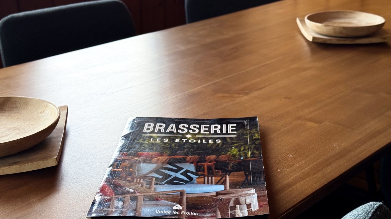 Ein Holztisch mit einer Zeitschrift mit dem Titel 'BRASSERIE LES ETOILES'.
