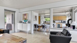A spacious living area with a wooden dining table, a black leather sofa, and a kitchen in the background. - 3 bedroom lovely home in Vig (Vig)