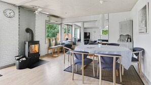 A cozy room with a fireplace, a dining table with chairs, and a television. - 3 bedroom lovely home in Vig (Vig)
