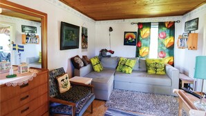 A cozy living room with a sofa, a wooden cabinet, a small table, and a chair. There are several cushions on the sofa, and a stuffed animal is visible. - Gorgeous home in Ambjörnarp with WiFi (Ambjörnarp)