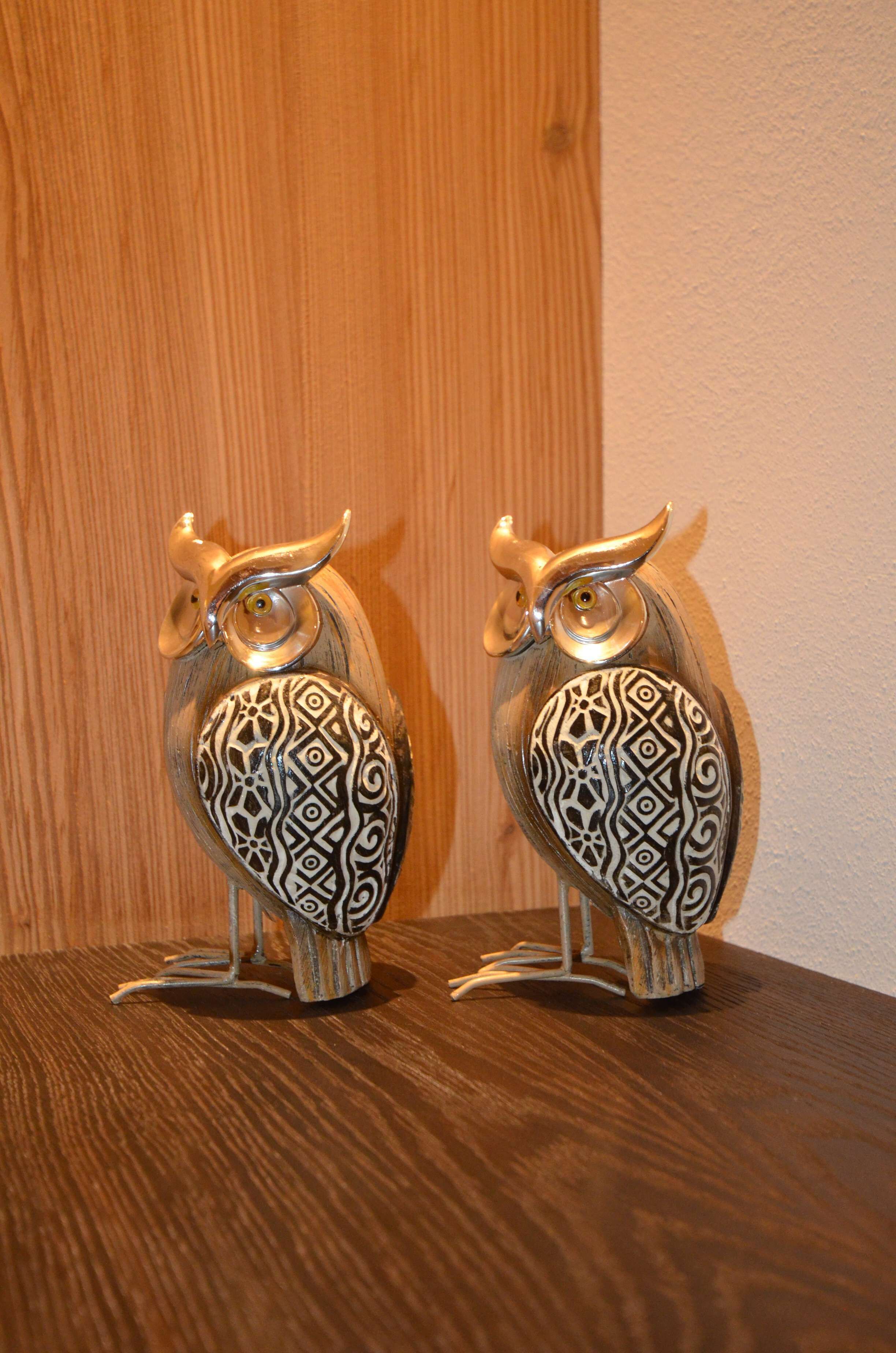 Two ornately designed owl figurines on a wooden surface.