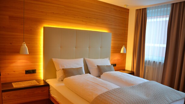 A neatly made double bed with a headboard, bedside tables, and a nightstand. - Exclusive mountain lodge style apartment - 90 m² - Free WIFI (Ortisei)