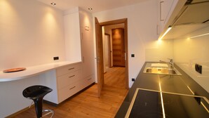 A modern kitchen with a black countertop, stainless steel sink, and wooden flooring. - Exclusive mountain lodge style apartment - 90 m² - Free WIFI (Ortisei)