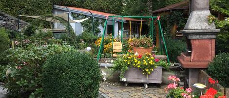 A garden with a swing set, potted plants, and a bird feeder.