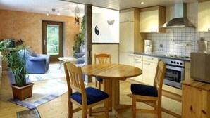 Una cocina moderna con armarios de madera, una estufa y un comedor con una mesa redonda y sillas.
