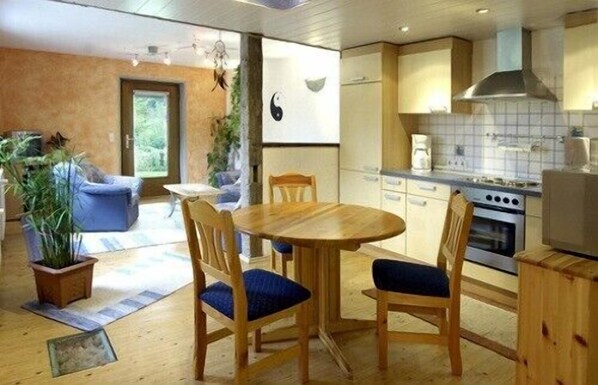 Une cuisine moderne avec des meubles en bois, une cuisinière et un coin repas comprenant une table ronde et des chaises.