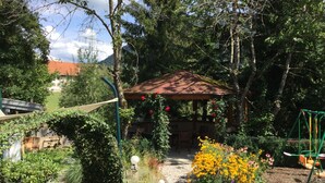 Un jardín con un porche, un sendero de piedra y una zona de estar al aire libre.