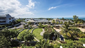 Un complex turístic amb piscina, palmeres i vista a l'oceà.
