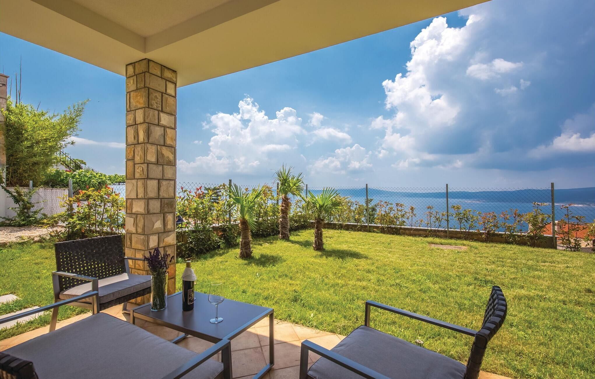 A patio with a stone pillar, outdoor furniture, and a view of the sea.