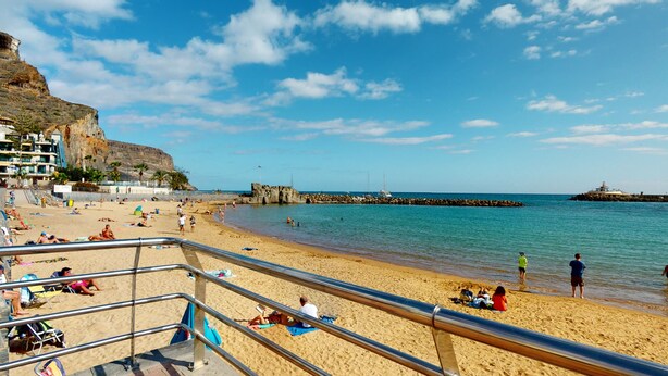 A beach with a rocky cliff, a pier, and a lighthouse. - Nice, modern apartment on the beach with sea view & terrace, free WiFi (Puerto de Mogan)