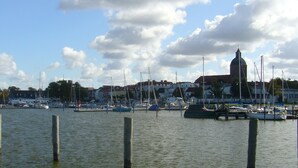 Un port de plaisance avec des bateaux amarrés, un clocher d’église imposant et des immeubles d’habitation en arrière-plan.
