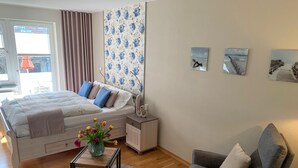 Une chambre à coucher avec un lit, une table de chevet, une chaise et une œuvre d’art accrochée au mur.