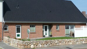 Una casa de ladrillo con techo oscuro, una puerta principal y un pequeño porche.