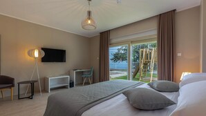 Une chambre d’hôtel équipée d’un lit, d’un bureau, d’une chaise, d’une télévision et offrant une vue sur l’extérieur.