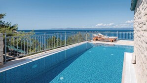 A clear blue pool with a view of the sea, surrounded by a white metal fence and a stone wall. - Gorgeous home in Prigradica with sauna (Prigradica)