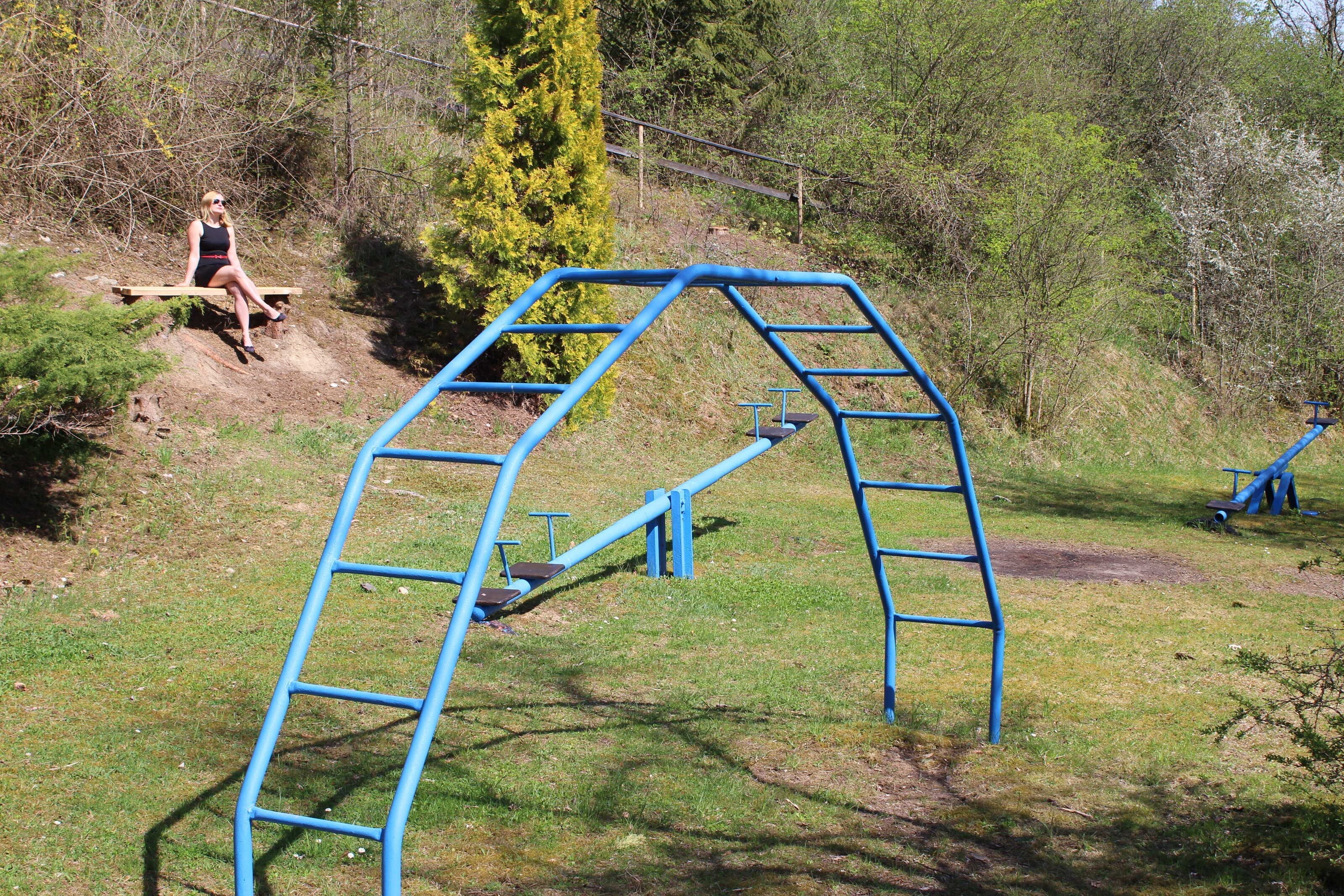 A playground with a blue climbing structure and a wooden bench.