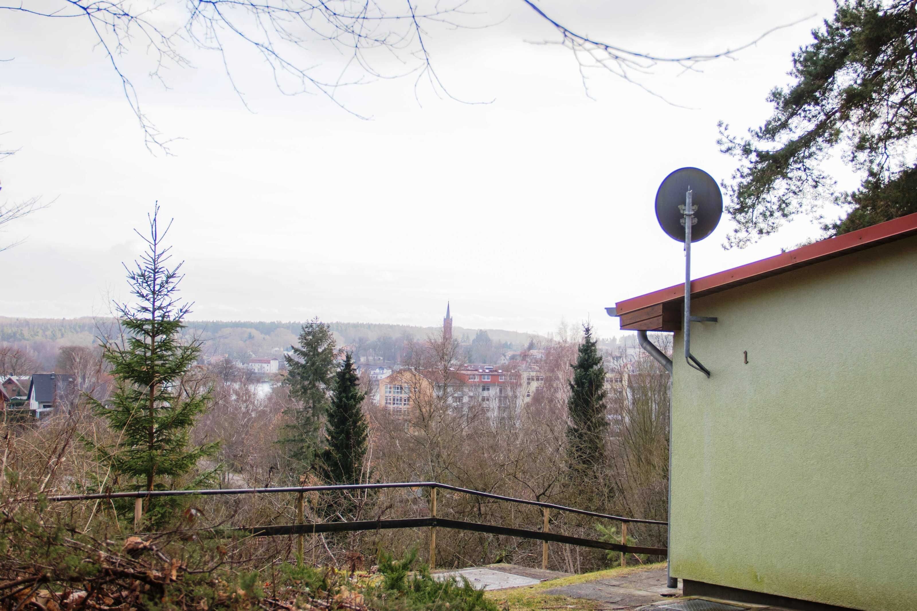 Un bâtiment doté d’une antenne parabolique, d’un toit rouge et offrant une vue sur une ville en arrière-plan.