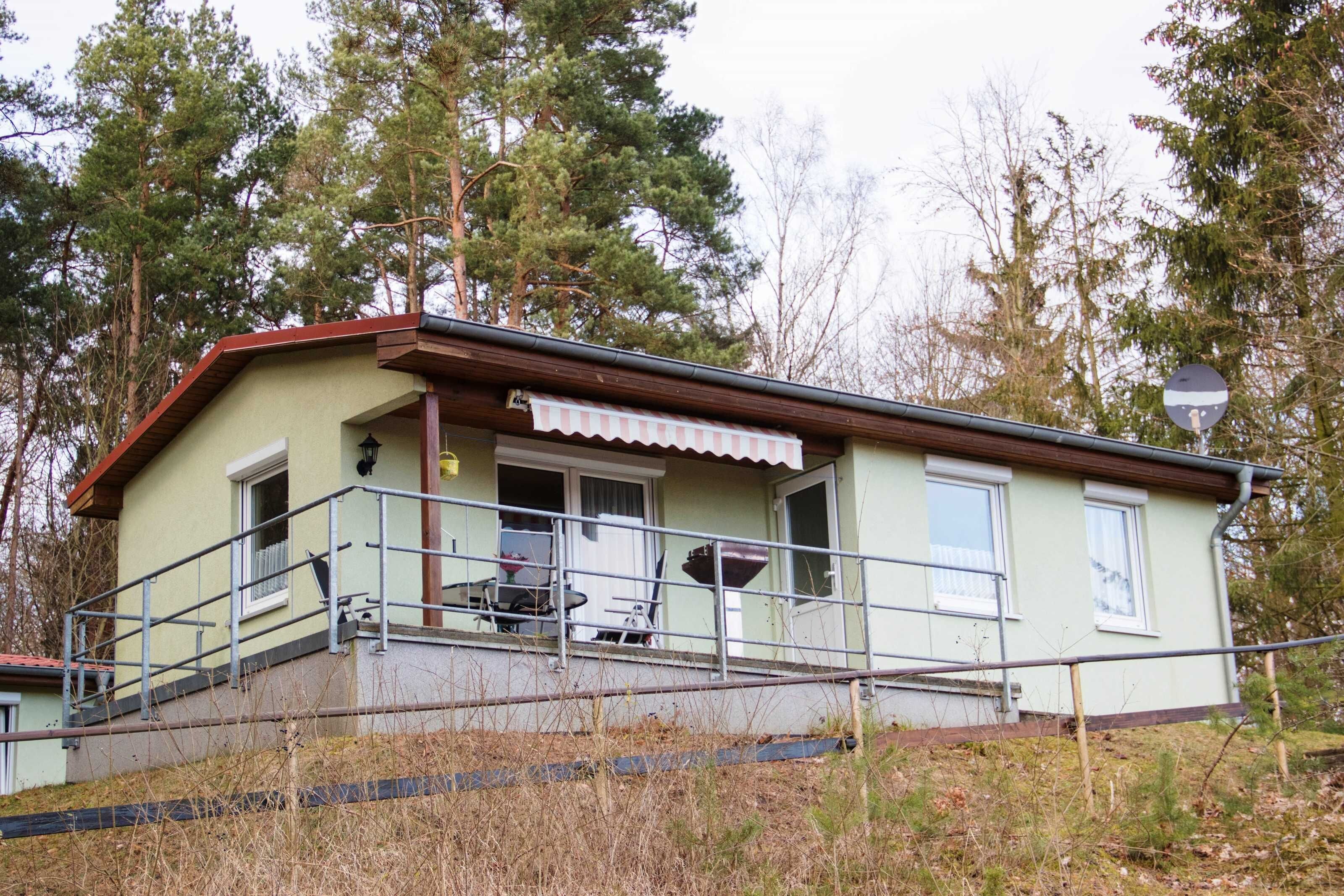 Un bâtiment d’un seul étage doté d’un porche, d’un petit espace extérieur aménagé avec des sièges et d’un escalier menant à l’entrée.