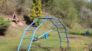 Ein Spielplatz mit einer blauen Kletterkonstruktion und einer Holzbank.