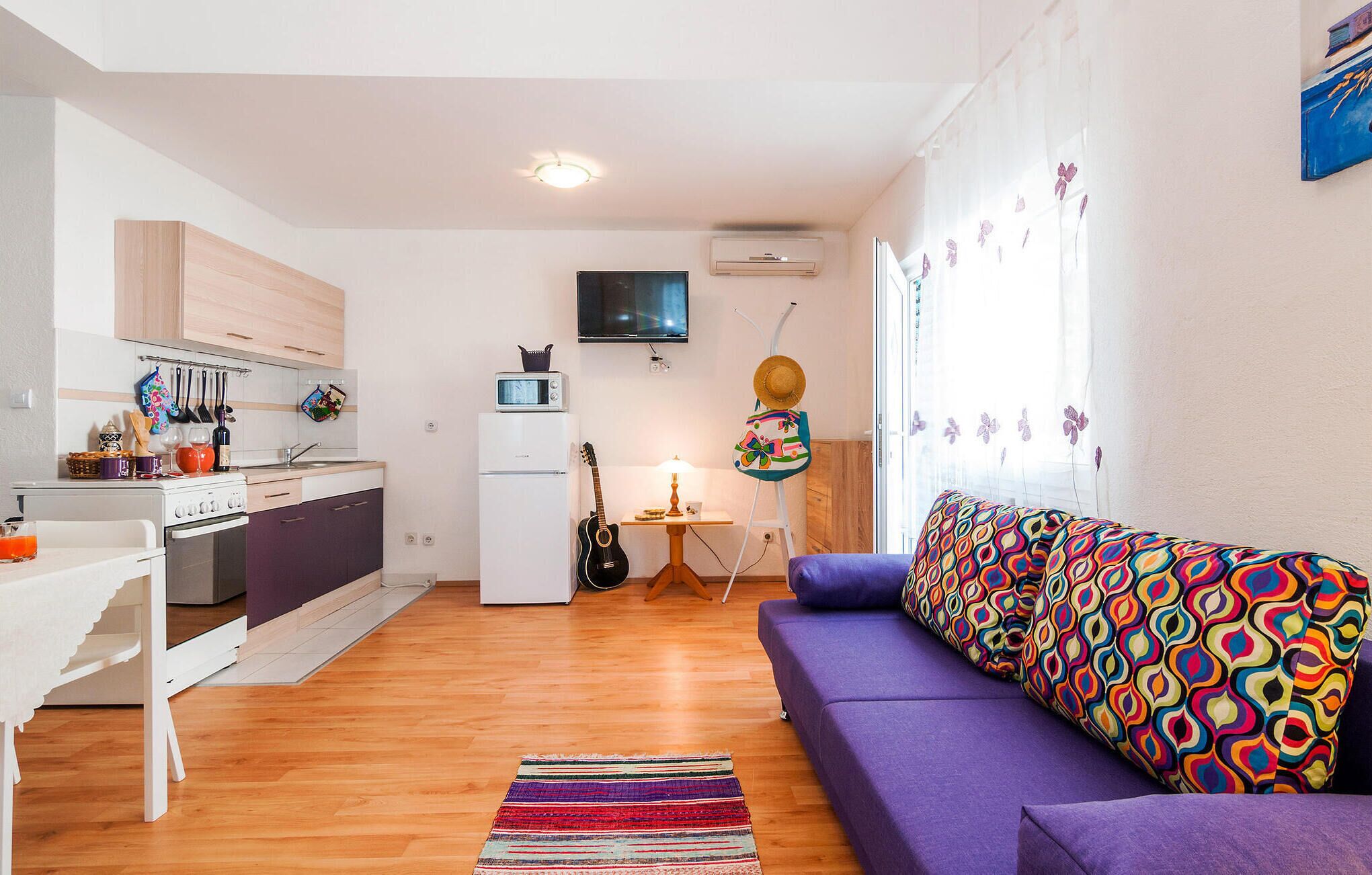 A compact living space with a kitchenette, a sofa, and a small dining area.