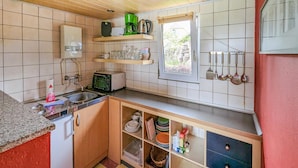 Una cocina compacta con microondas, tostadora y ventana con vista a la vegetación.