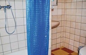 Een badkamer met een douche, een wastafel en een betegelde vloer.