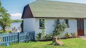 Un pequeño edificio blanco con techo verde, una puerta de madera y una ventana.