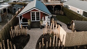 Ein Wohngebiet mit mehreren Häusern, darunter ein zentral gelegenes rotes Haus mit Veranda und einem eingezäunten Garten.