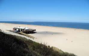 Eine Strandlage mit einem Steg, einem kleinen Gebäude und freiem Blick auf das Meer.