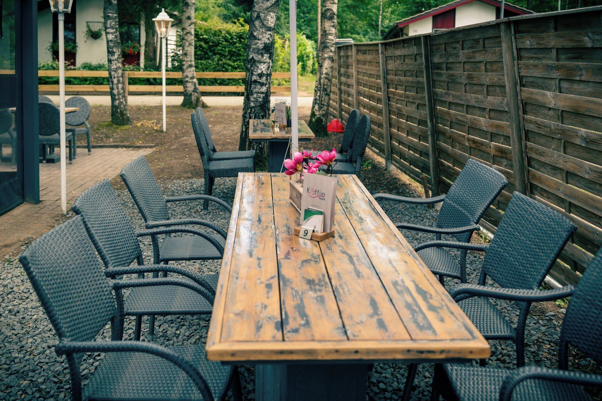 A wooden table with eight chairs, a sign with the number 9, and a flower arrangement.