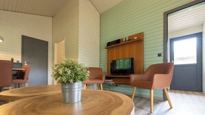 Una habitación acogedora con una mesa de madera, dos sillas marrones, un televisor y una planta en maceta.