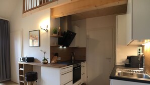 Cocina compacta con microondas, estufa, fregadero y una pequeña isla con una planta.