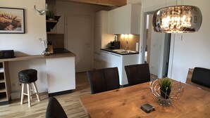 Una cocina moderna con armarios blancos, una mesa de comedor de madera y una araña.