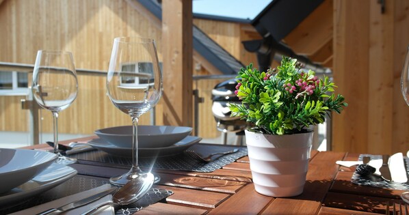 A dining table set with plates, cutlery, and wine glasses, with a potted plant in the center.