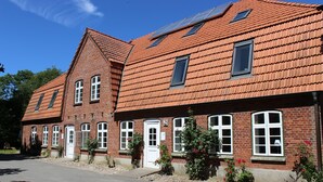 A red-brick building with multiple windows and a sloped roof. - Vacation apartment Matrosennest - OSTSEE-Ferienwohnungen (Hasselberg)