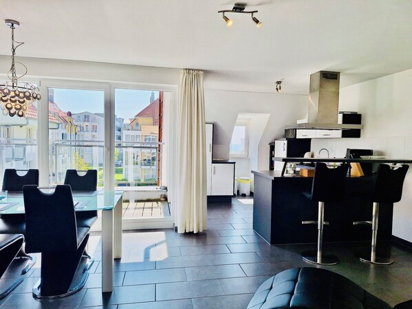Un apartamento moderno con comedor, cocina y ventanas amplias que ofrecen vista a la ciudad.