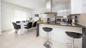 A modern kitchen with a central island, bar stools, and a dining area with chairs and a table. - Beautiful home in Kastel Stafilic with sauna (Kastel Stafilic)