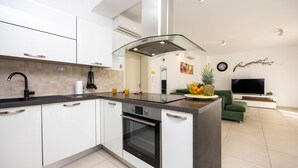 A modern kitchen with white cabinetry, a black oven, and a glass cooktop island. - Beautiful home in Kastel Stafilic with sauna (Kastel Stafilic)