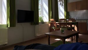 Olohuone, jossa on televisio, ruokapöytä, tuoleja ja patteri.