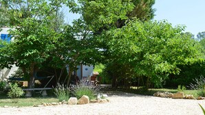 Ein Garten mit Kiesweg, einer Bank und einem Tisch unter einem Baum.