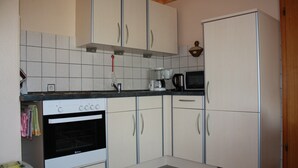 Una cocina con armarios blancos, estufa, microondas y refrigerador.