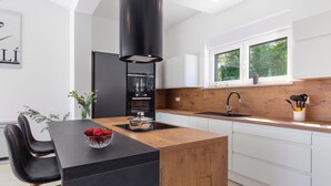 A modern kitchen with a central island, black appliances, and a wooden countertop. - Awesome home in Kujici with sauna (Kujici)